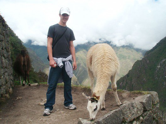 Student with llama on educational tour in Machu Picchu, Peru