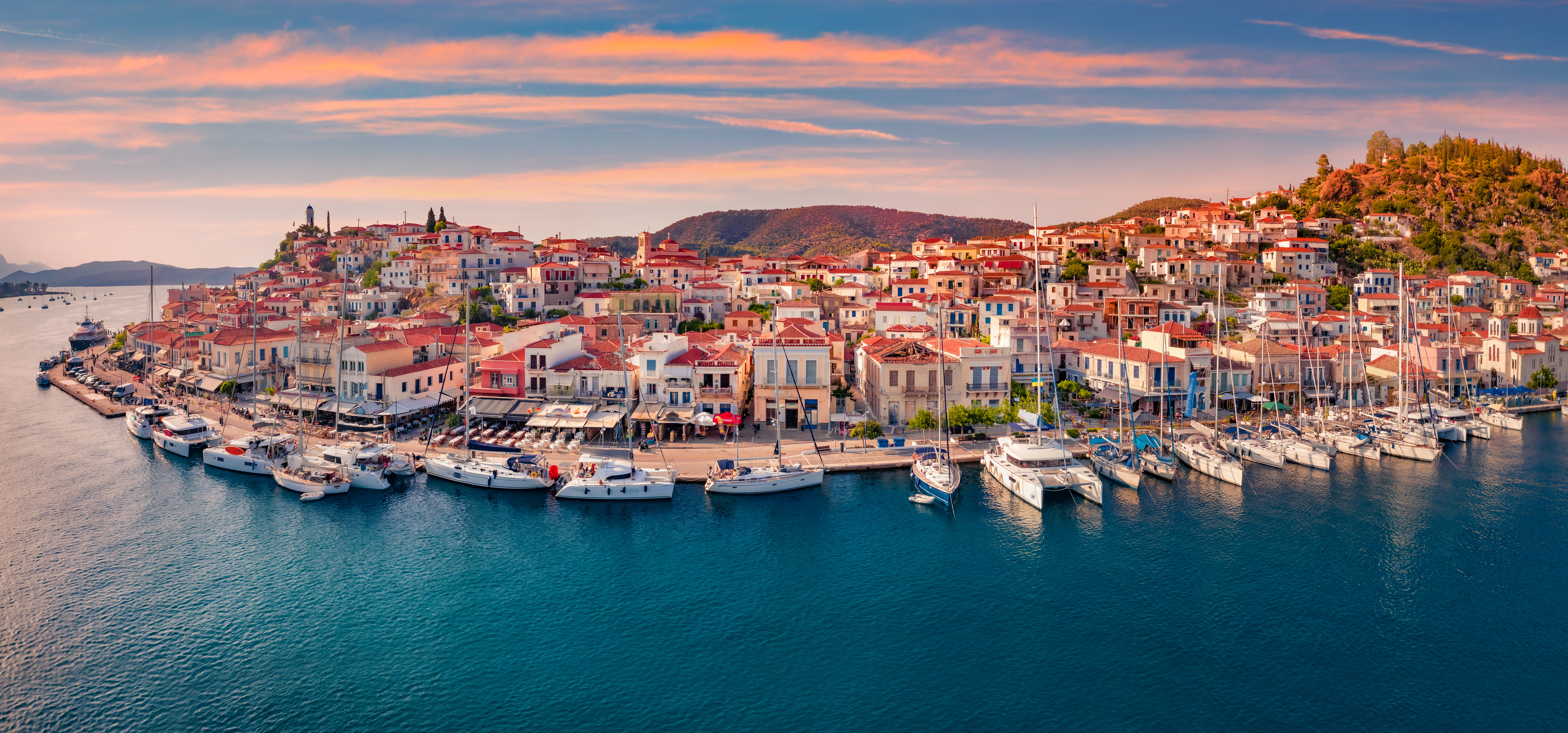 Fantastic sunset in Poros town. Picturesque summer seascape of Myrtoan Sea with a lots of yachts. Attractive evening scene of Peloponnese peninsula, Greece. Traveling concept background.