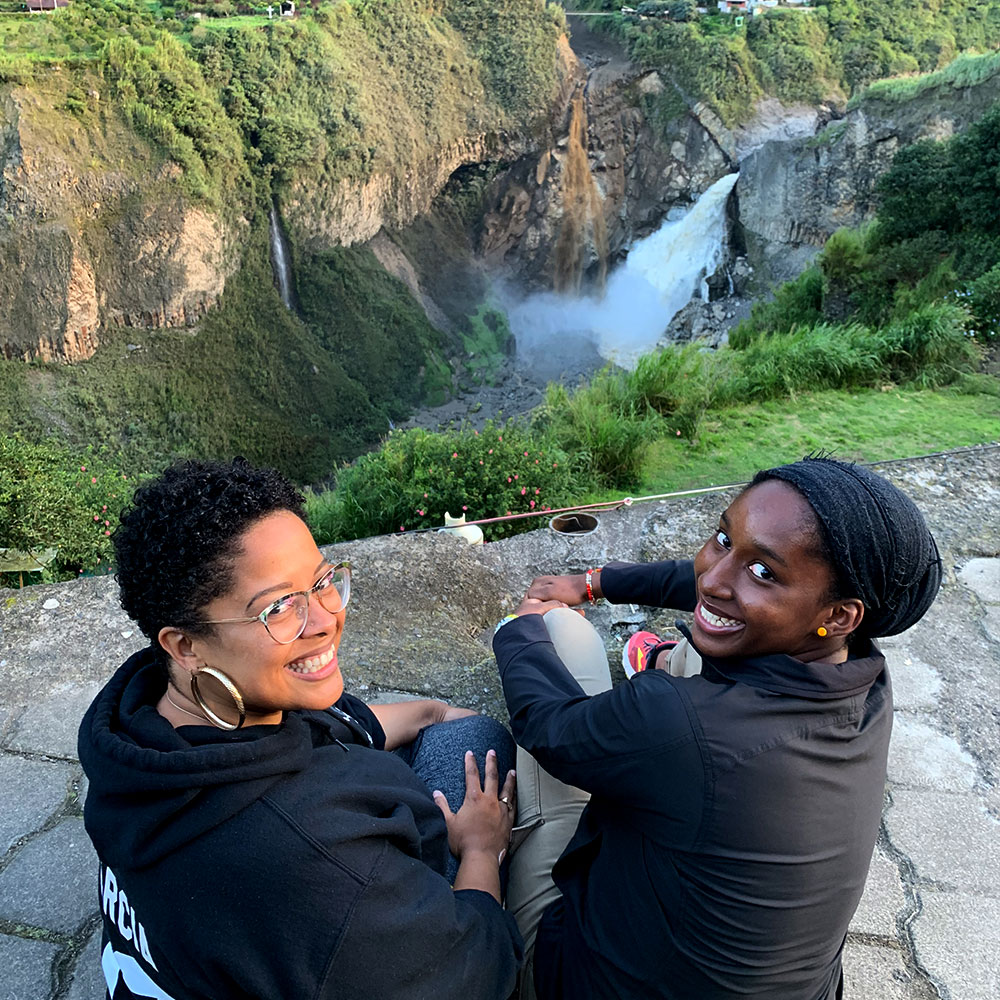 two joy-filled women at the edge of a beautiful mountain with a misty river in the distance