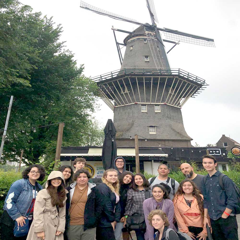 a group of teachers smiling with a windmill in the distance